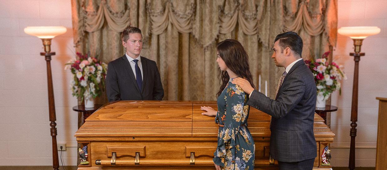 学生 standing next to a casket at a mock funeral